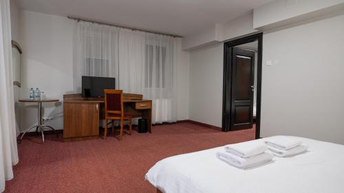 a hotel room with a bed and a desk and a television at Forrest in Głogów Małopolski