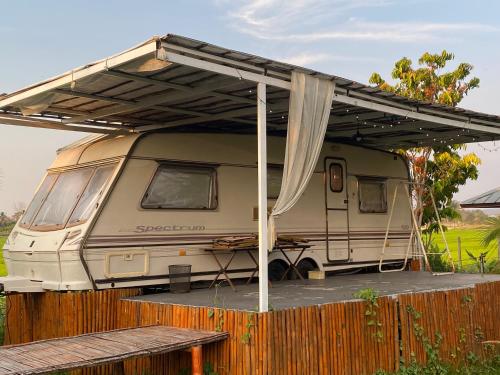 a rv parked under a canopy on a fence at At HuG in Ban Muang Chum