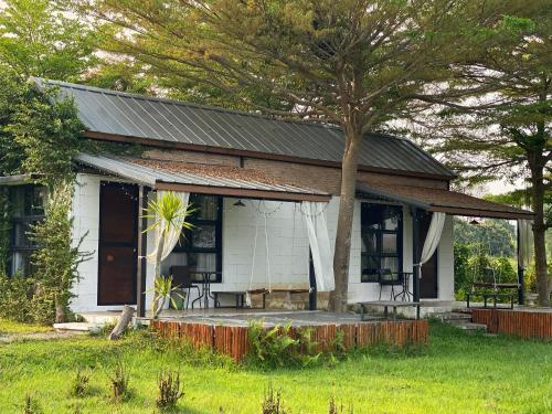 a white house with a tree in front of it at At HuG in Ban Muang Chum