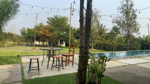 a patio with a table and chairs next to a pool at At HuG in Ban Muang Chum
