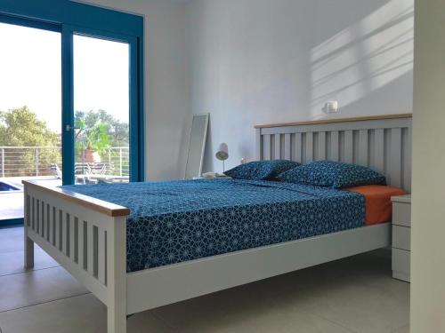 ein Schlafzimmer mit einem Bett mit blauer Bettdecke und einem Fenster in der Unterkunft Villa Mandarini in Kamilari