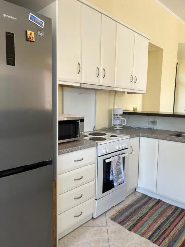 a kitchen with white cabinets and a stainless steel refrigerator at Sunshine 2 in Leonidion