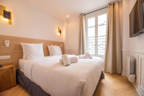 une chambre avec un grand lit blanc avec une fenêtre dans l'établissement Lovely Flat near Rue Crémieux & Bastille, à Paris
