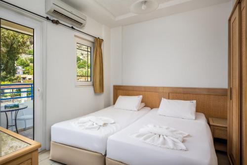 a bedroom with two beds and a balcony at Evi Studios & Apartments Pefkos in Pefki Rhodes