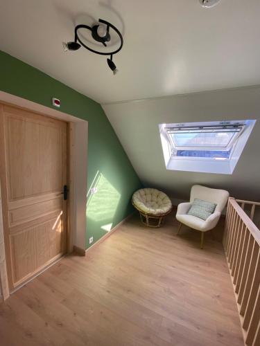 a attic room with a skylight and a chair and stairs at Gite Le Petit Nid - 3 chambres in Couvin