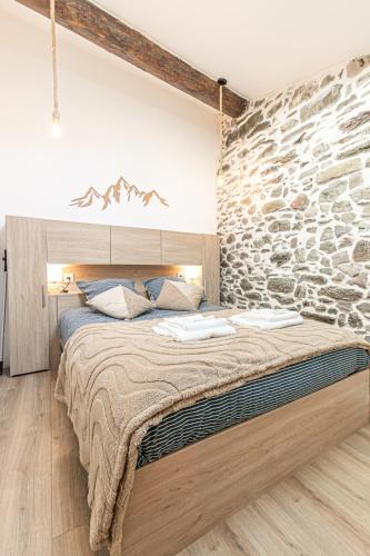 une chambre avec un grand lit avec un mur en pierre dans l'établissement Appartement proche La norma Aussois, à Villarodin-Bourget