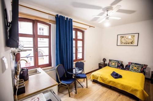 a bedroom with a yellow bed and a table and chairs at Planetarium - Stare Miasto, Parking Free in Toruń