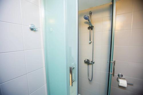 a shower with a glass door next to a toilet at Planetarium - Stare Miasto, Parking Free in Toruń