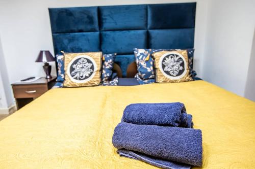 a bed with a blue headboard and two towels on it at Planetarium - Stare Miasto, Parking Free in Toruń