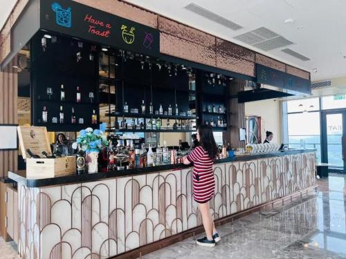a woman standing at a bar in a mall at Àlacarte Ha Long Bay Apartment - Golden Horizon in Ha Long