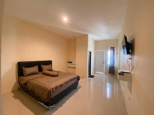 a bedroom with a bed and a flat screen tv at KS Guest House in Cilacap
