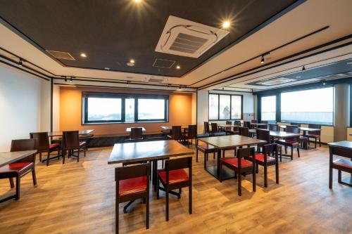 a dining room with tables and chairs and windows at Hotel Castle Inn Ise Meotoiwa in Ise