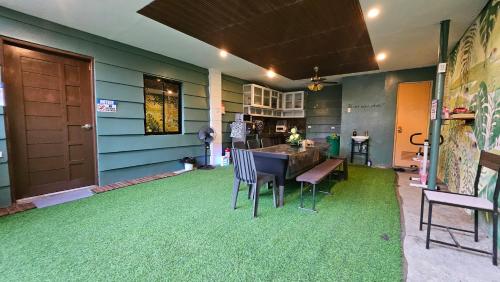 a dining room with a table and chairs on a green floor at Natural Haven with Netflix Kubo Videoke & Alfresco Dining in Dasmariñas