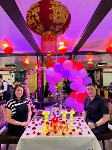 a man and woman sitting at a table with a birthday cake at Mila Cruises in Ha Long