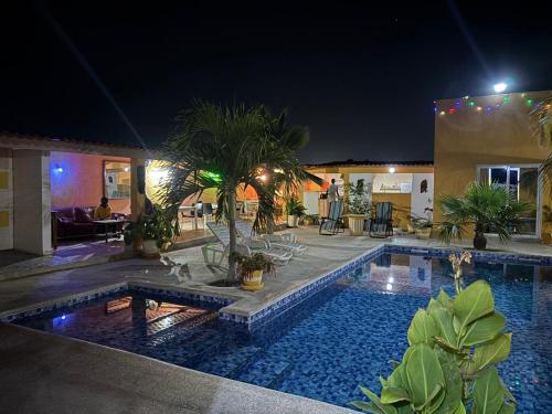 a swimming pool with palm trees in a house at night at Hôtel Colibri Lac Rose in Niaga