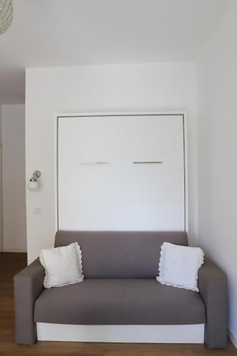 a grey couch with two white pillows on it at Valeria Apartment in Monza