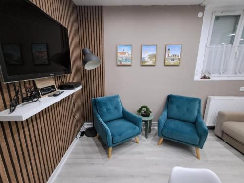 un salon avec deux chaises bleues et une télévision dans l'établissement Home Sweet Home, à Calais