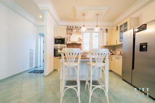 a kitchen with white stools and a black refrigerator at Victory's Luxury House with Jacuzzi on the Roof in Ischia