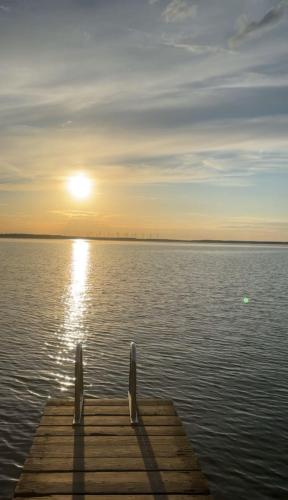 a dock on a body of water with the sun setting at Zum Waldblick in Funfseen