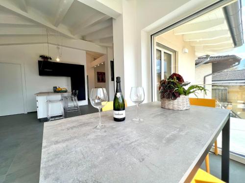 a table with two wine glasses and a bottle of wine at Attico del Lago - Levico in Levico Terme