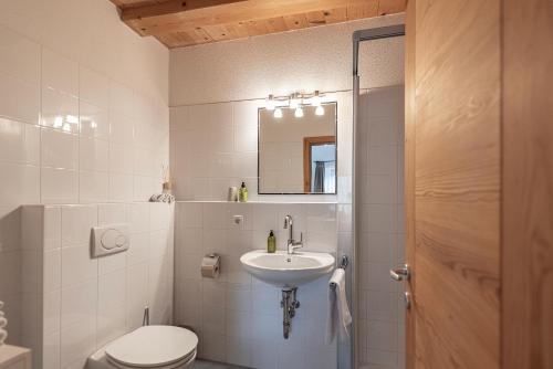 a bathroom with a sink and a toilet and a mirror at Schrotthof in Feldthurns