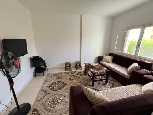 ein Wohnzimmer mit einem Sofa und einem Ventilator in der Unterkunft Doblex Beach Chalet with Private Garden in Reem ElFala Resort in El-Alamein
