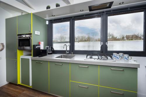 a kitchen with green cabinets and a large window at Aangenaam op de Rijn, woonboot, inclusief privé sauna in Alphen aan den Rijn