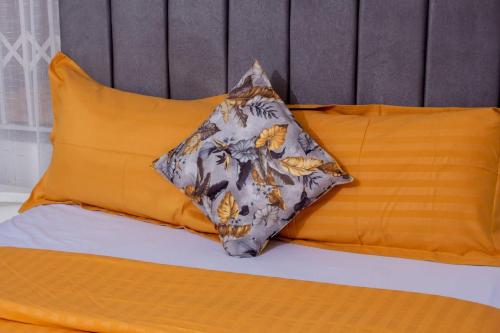 a pillow sitting on a bed with two orange pillows at Holiday Home, Zimre Park, Harare, Zimbabwe in Harare