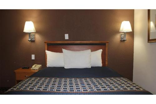 a bed in a hotel room with two lamps and a phone at Travel Inn By OYO Omaha in Omaha