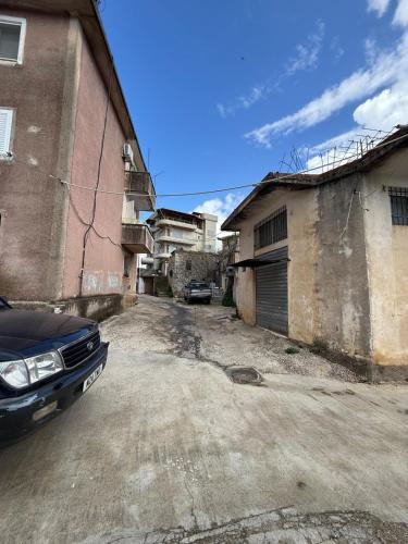 an empty street with a car parked next to buildings at 2 bedroom flat in shënvasil in Shënvasi