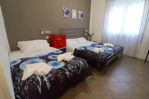 a bedroom with two beds and a red suitcase at Fasthotel in Cervia