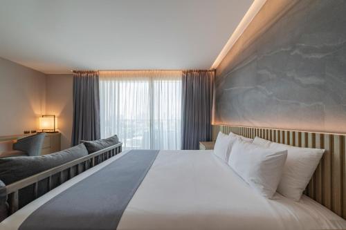 a hotel room with a large bed and a window at Mandarin Eastville, Pattaya - SHA Extra Plus in Pattaya North