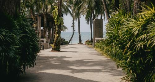 a pathway with palm trees and the ocean in the background at The Dewa Koh Chang in Ko Chang