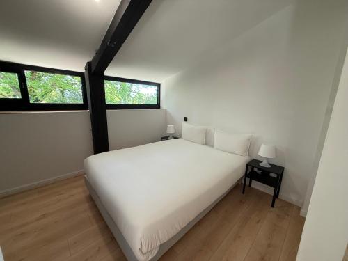 una camera con un letto bianco e due finestre di Villa avec piscine a Montauban