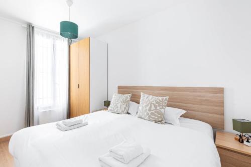 une chambre blanche avec un grand lit blanc avec des oreillers dans l'établissement GuestReady - Stylish Escape in Folie-Méricourt, à Paris