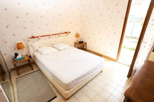 une chambre avec un lit blanc avec une fenêtre dans l'établissement St Cyprien maison de vacances 6 personnes clim, à Saint-Cyprien