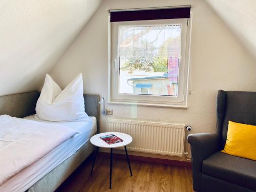 Ferienwohnung Kinnerstuw في بريرو: غرفة نوم بها سرير وكرسي ونافذة