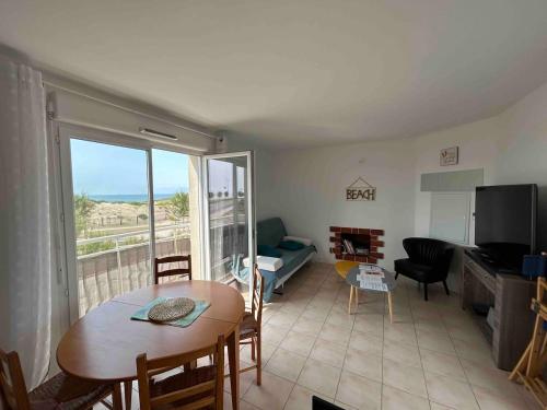 d'un salon avec une table et d'une chambre avec un balcon. dans l'établissement Maison front de mer, vue océan, à Soulac-sur-Mer