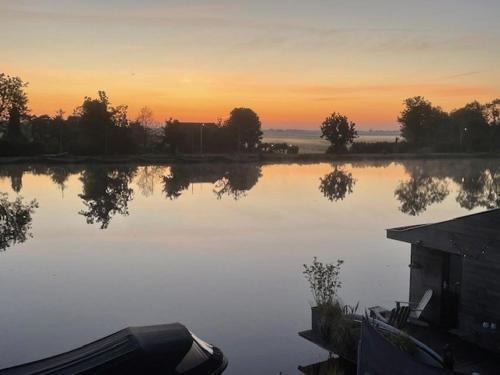 莱茵河畔阿尔芬Aangenaam op de Rijn, woonboot, inclusief privé sauna的一大片水体,背景是日落