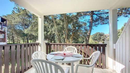 - une table et des chaises blanches sur une terrasse couverte dans l'établissement M-Bruyère 02-Moliets Charmant appartement pour 4 personnes proche golf et plage dans un résidence avec piscine, à Moliets-et-Maa