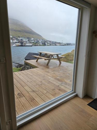 a picnic table on a deck with a view of the water at Sea View Suite in Klaksvík