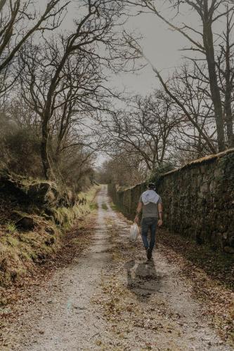 a man walking down a dirt road next to a stone wall at Casal Oseira in Ourense