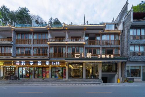 a large building with shops in front of a street at Phoenix Mandu River View Homestay in Fenghuang