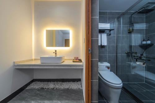 a bathroom with a sink and a toilet and a mirror at Phoenix Mandu River View Homestay in Fenghuang