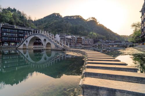 a bridge over a body of water with buildings at Phoenix Mandu River View Homestay in Fenghuang