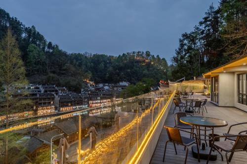 a balcony with tables and chairs overlooking a train track at Phoenix Mandu River View Homestay in Fenghuang