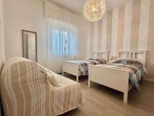 Un dormitorio con dos camas y una lámpara de araña. en Charming apartment just two steps from the sea, en Lido di Camaiore