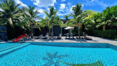 a swimming pool with a slide in front of a house at Coco Pina in Prachuap Khiri Khan