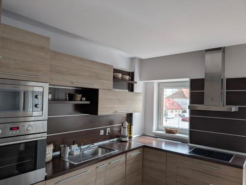 a kitchen with wooden cabinets and a sink and a window at Apartament central 3 dormitoare in Tîrgu Secuiesc
