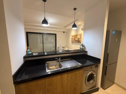 a kitchen with a sink and a washing machine at Lynda in Nabeul